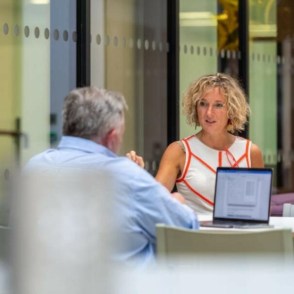 two people sitting at a laptop in a meeting room