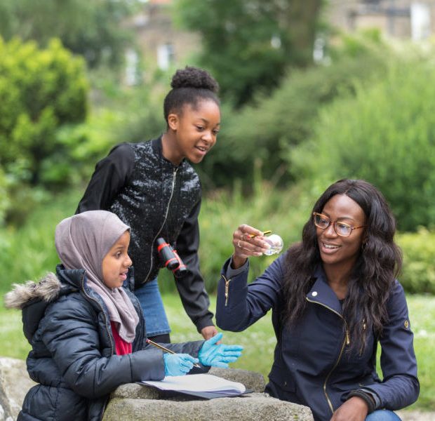 2 young schoolgirls and one teacher doing a joint project in White City about planting/greening